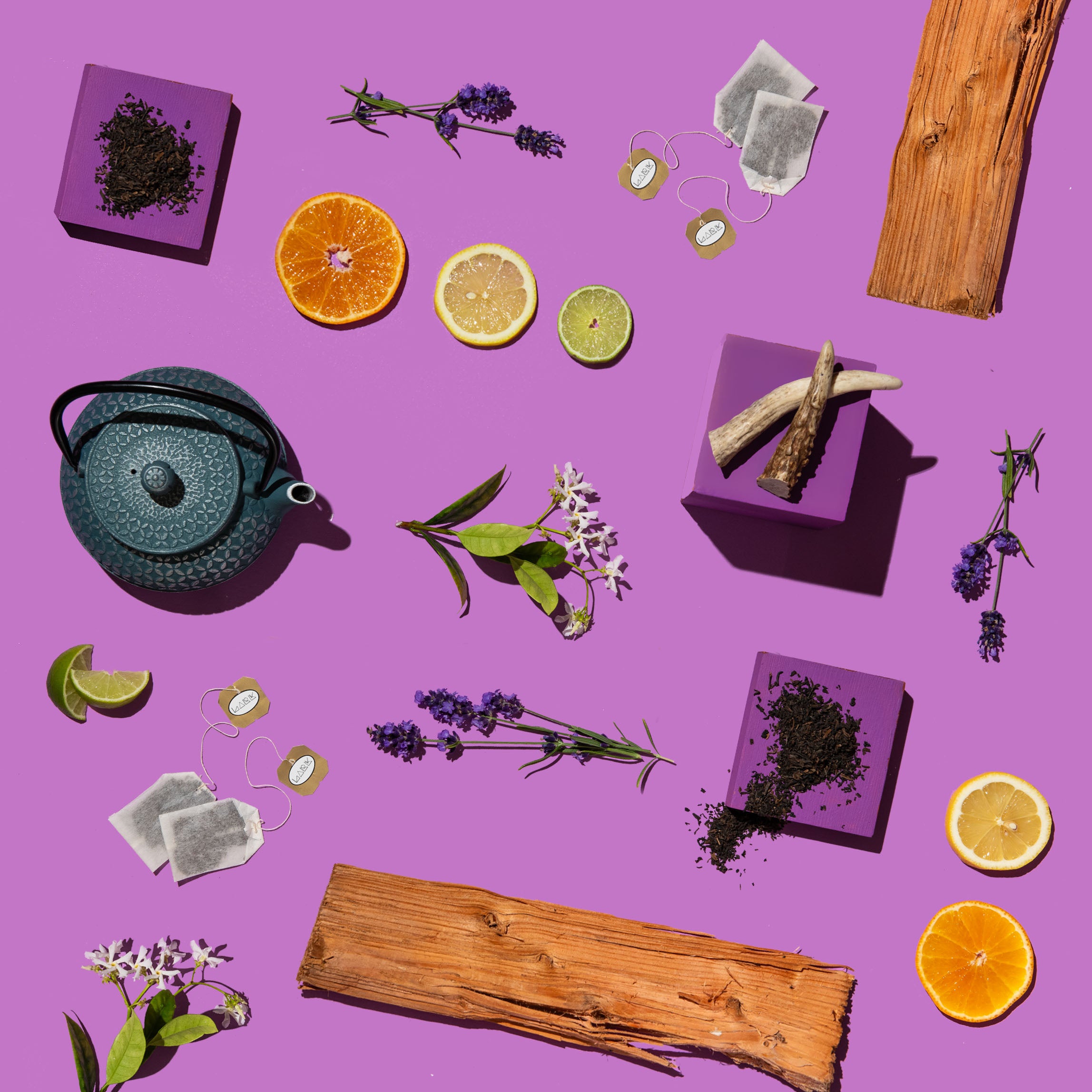 Tea-making items including a teapot, tea leaves, citrus fruits, and herbs on a purple background