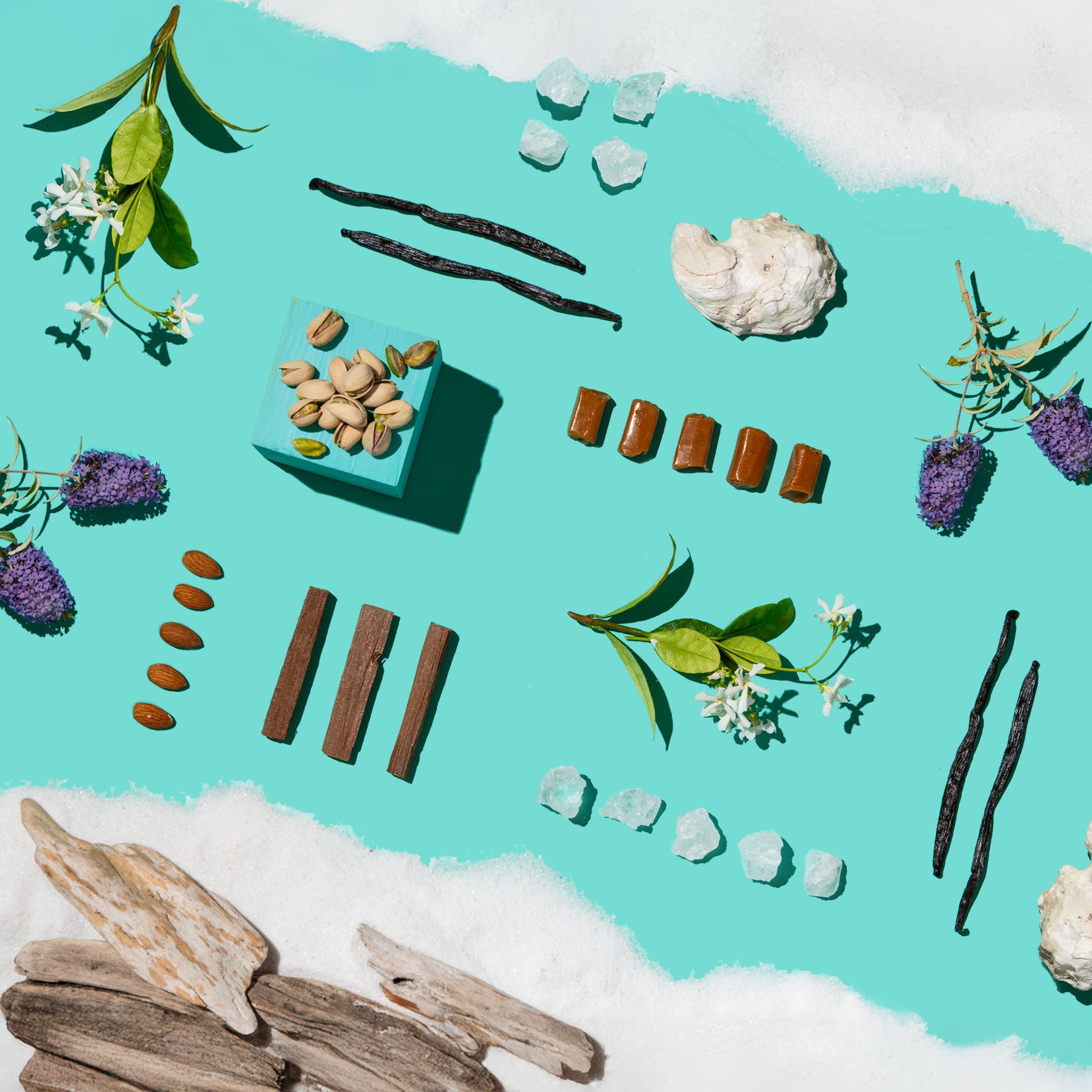 Spices, herbs, and crystals arranged on a turquoise background with white sand.
