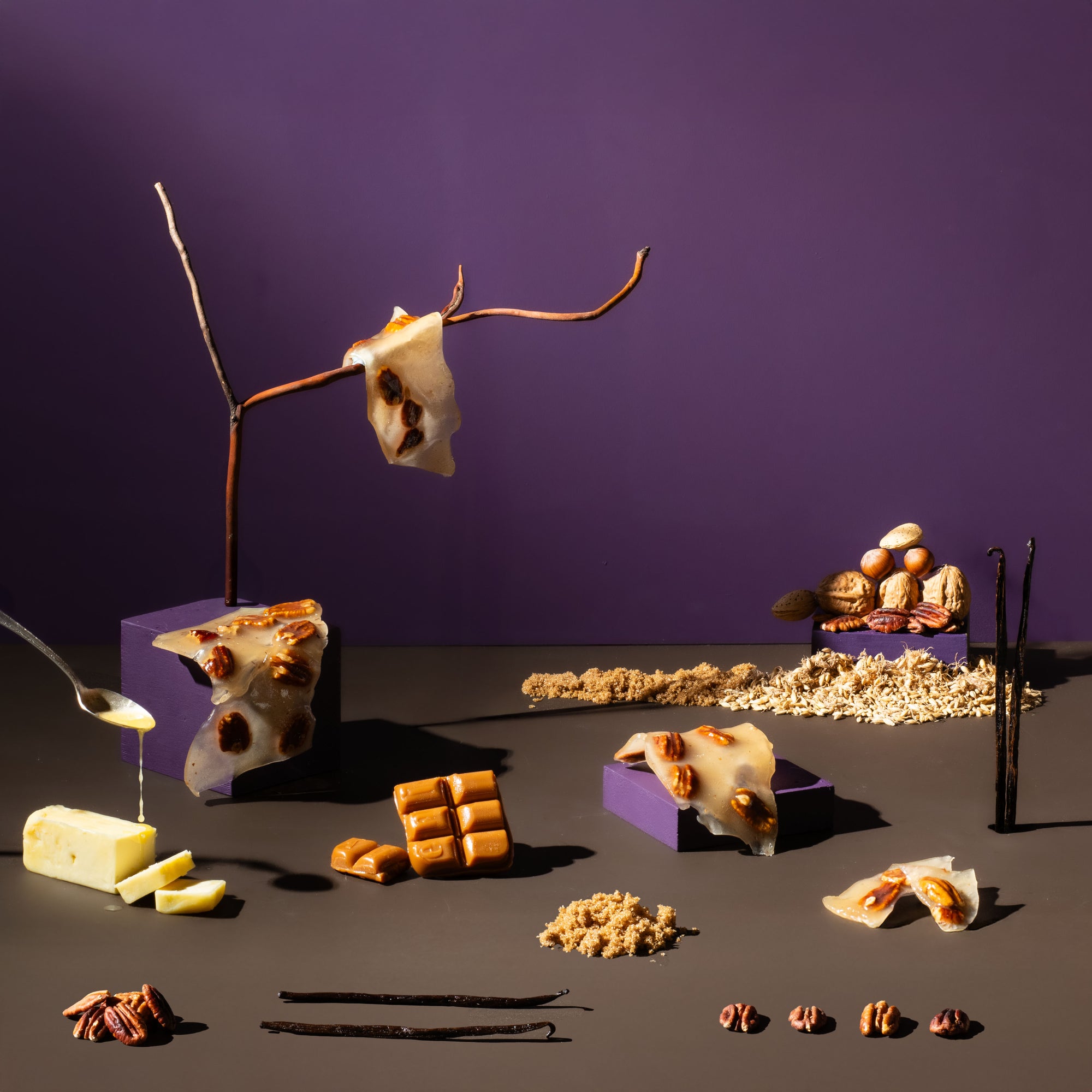Assorted food items including cheese, nuts, and chocolate bars on a dark surface with a purple background.