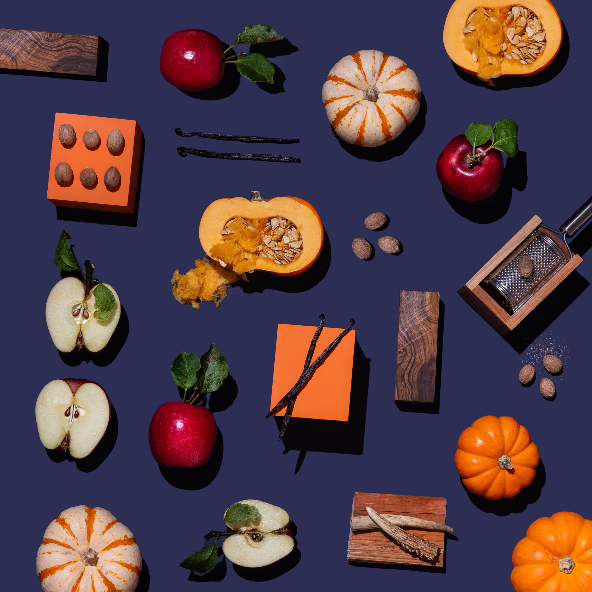 Various kitchen items including pumpkins, apples, and a grater on a dark blue background