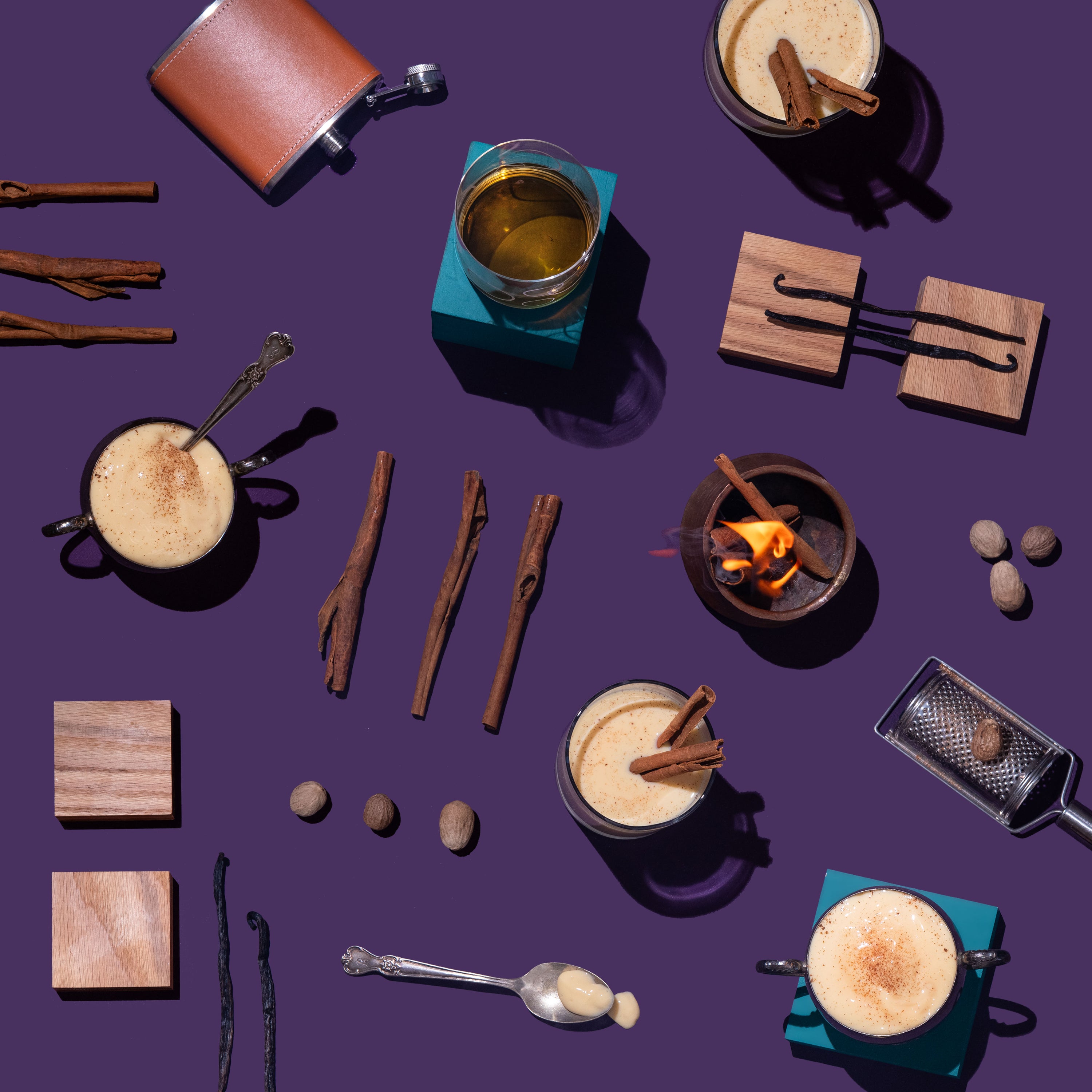 Frothy Egg Nog with cinnamon sticks, vanilla beans, and a grater on a purple background