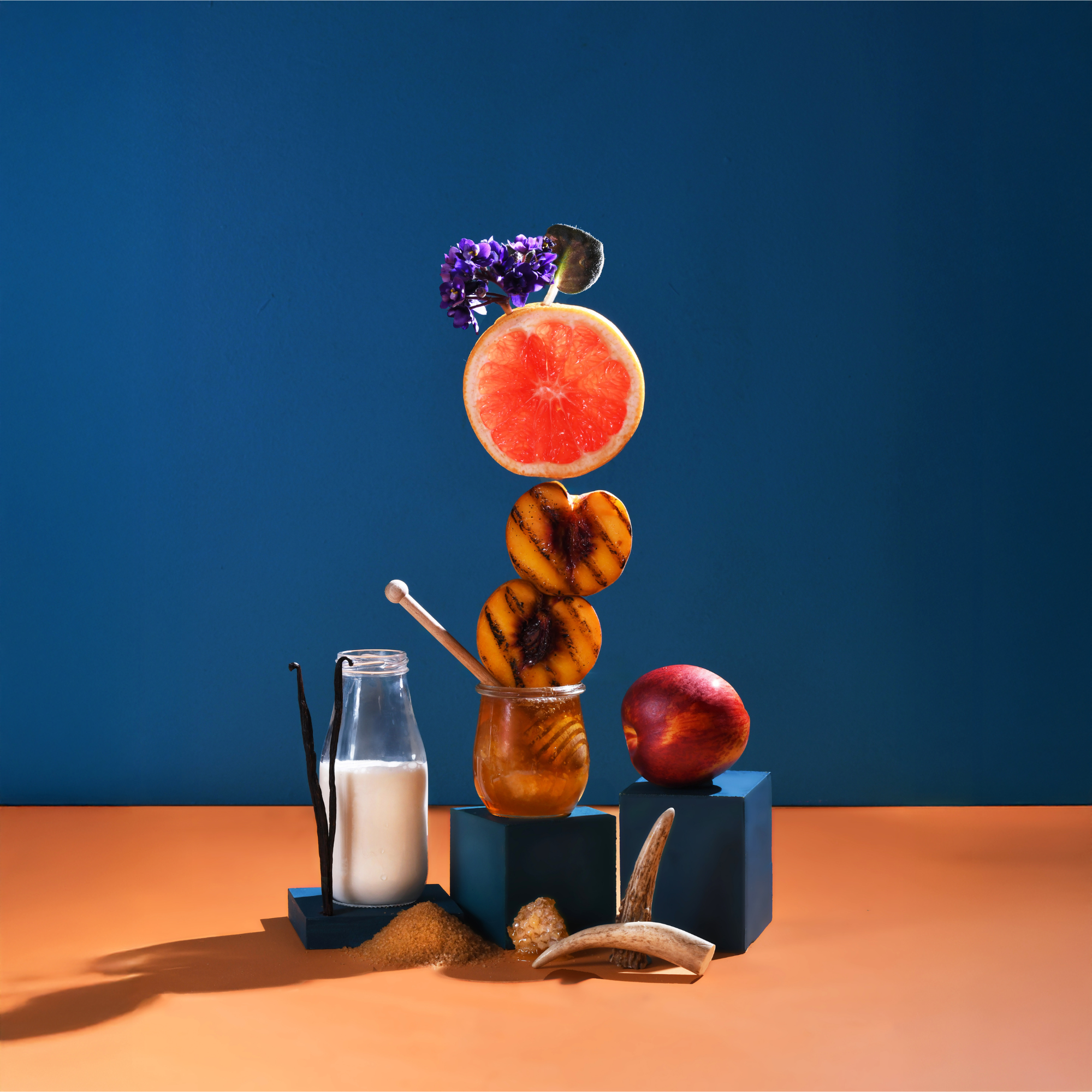 Stack of fruits and a bottle on a blue and orange background