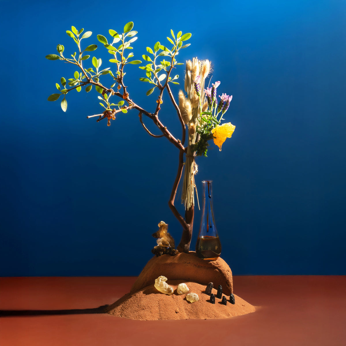 Miniature landscape with a tree, flowers, and small figures against a blue background