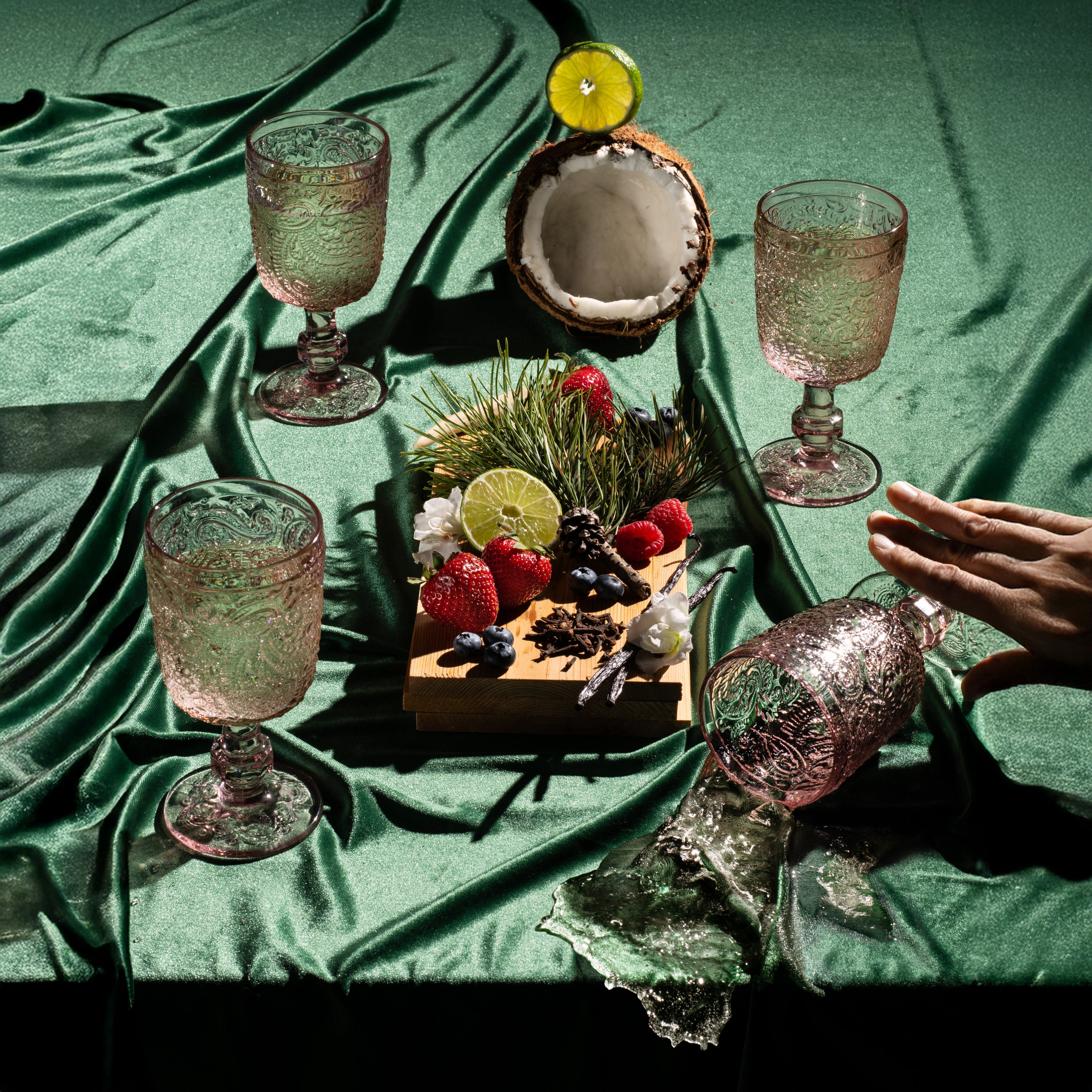 Cocktail glasses and a tropical fruit platter on a green fabric surface