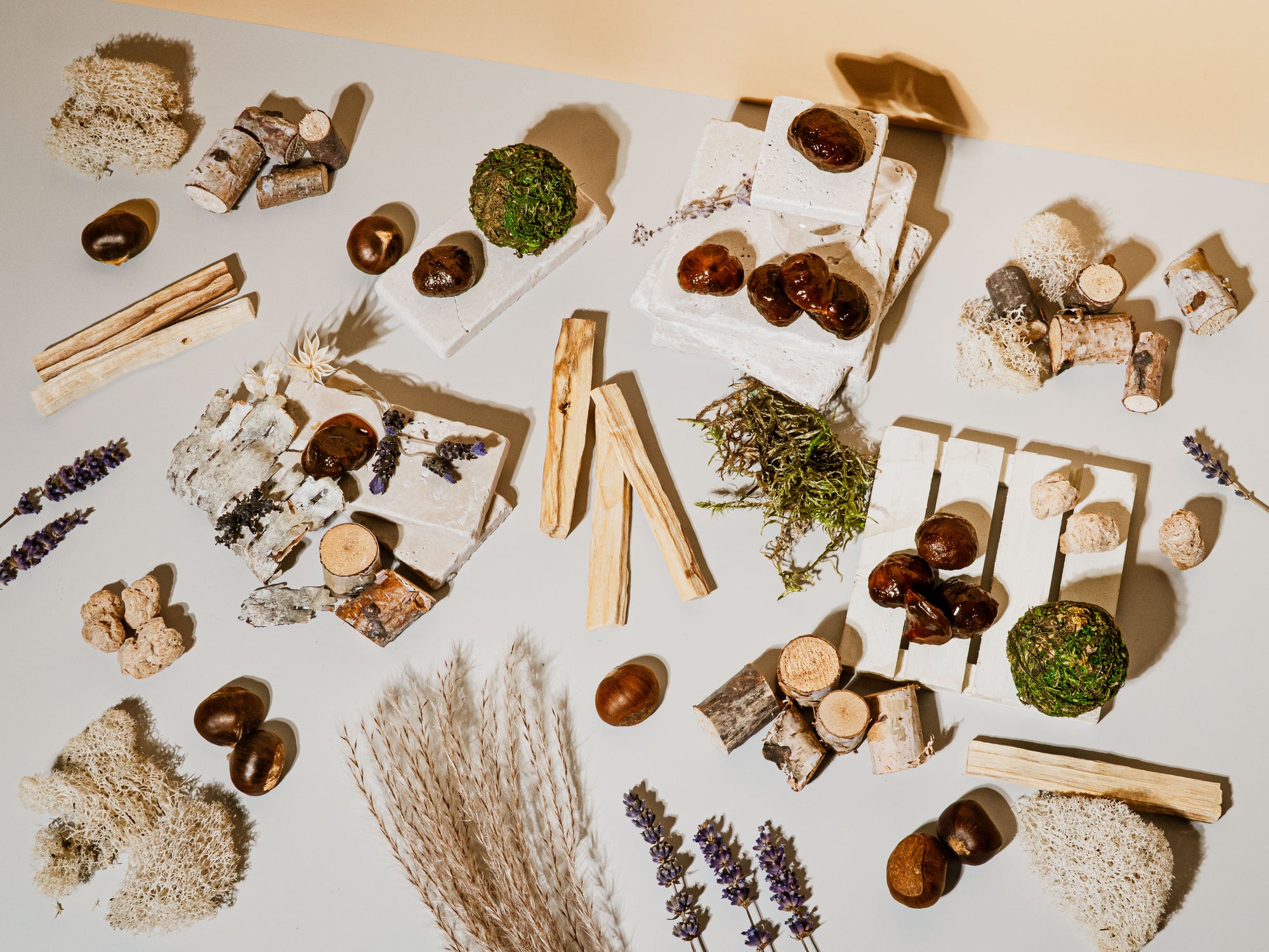 Arrangement of natural items including stones, herbs, and wooden elements on a light surface.